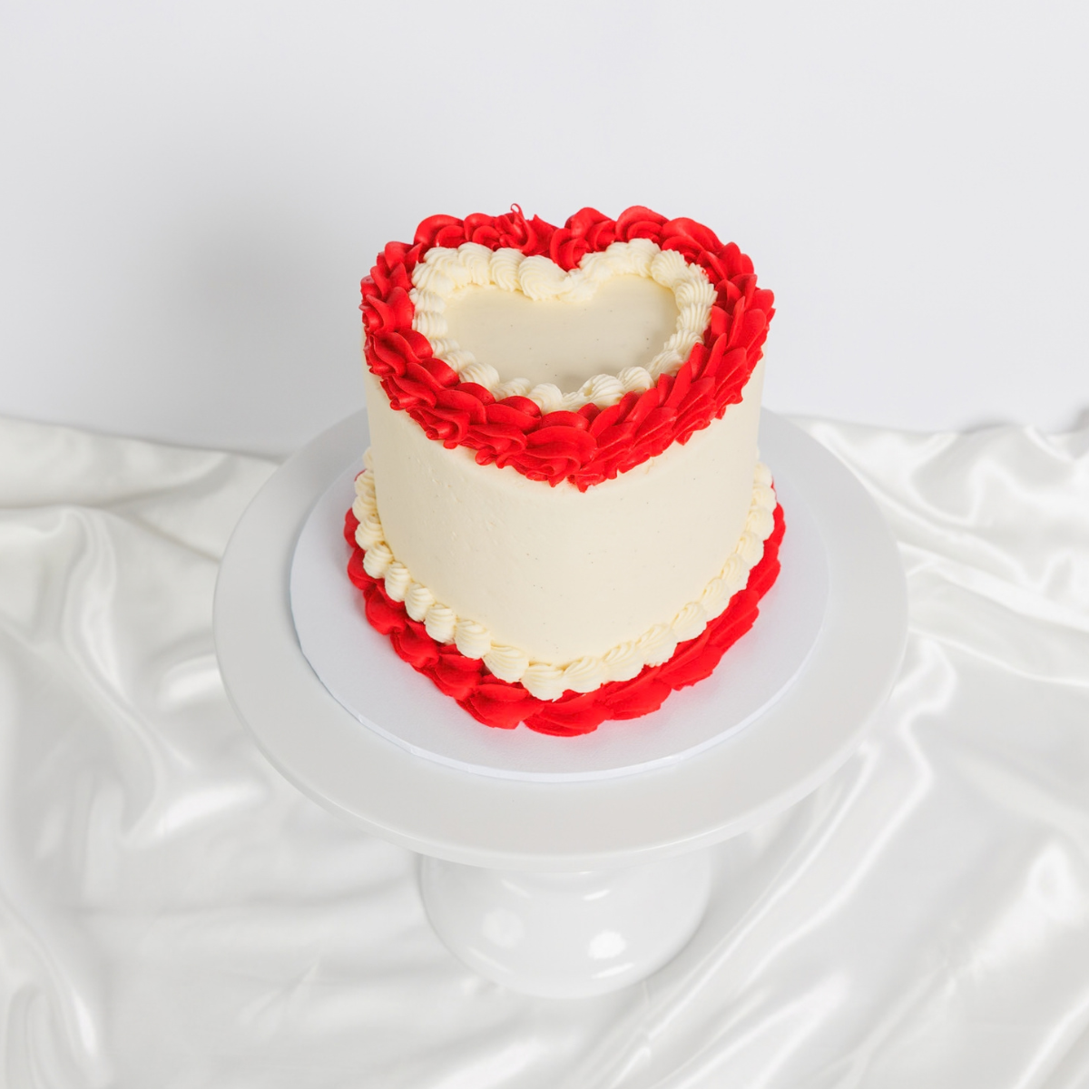 Three white Vintage Heart Cakes with yellow, black and red buttercream trim by The Cupcake Queens