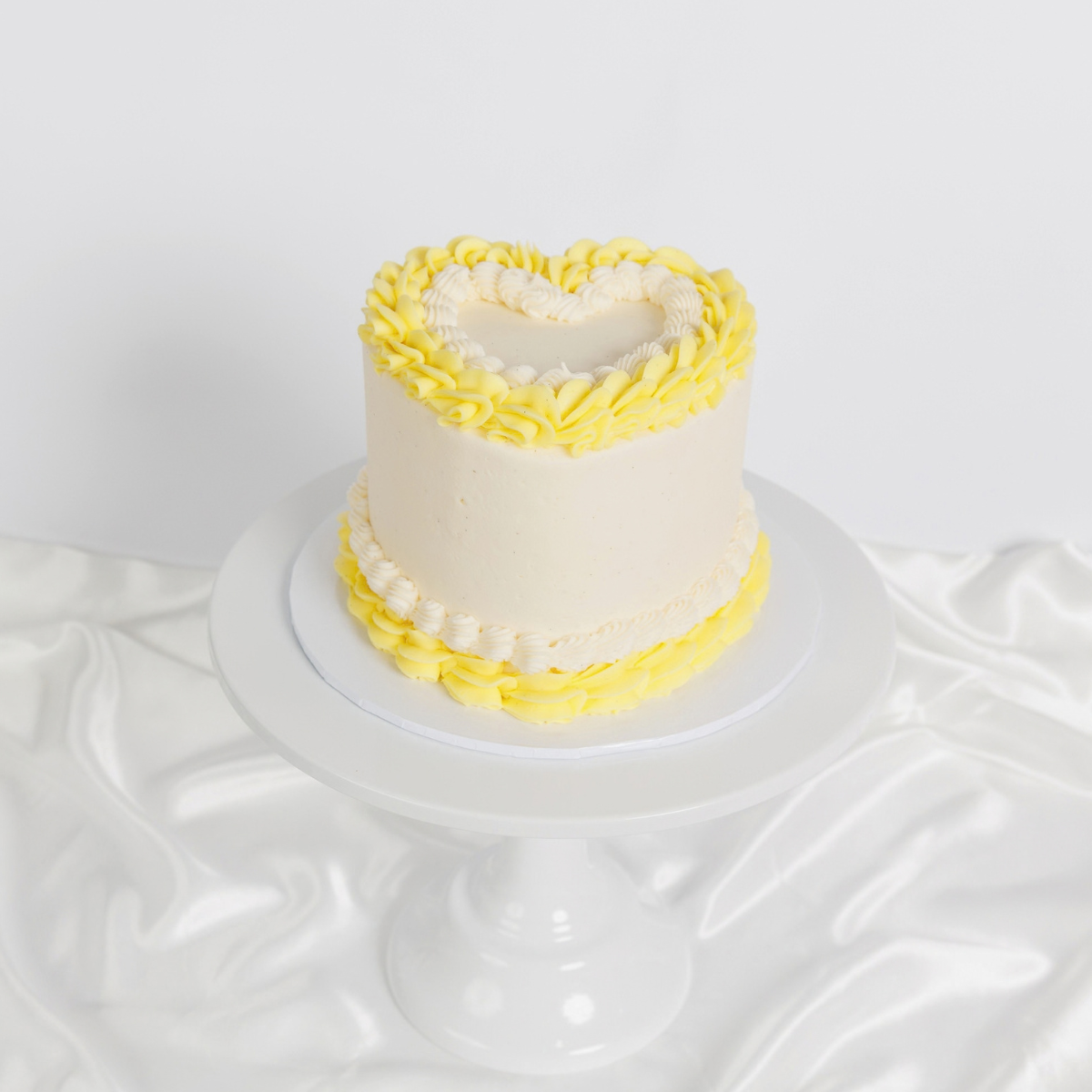 White Vintage Heart Cake with yellow buttercream trim, side view