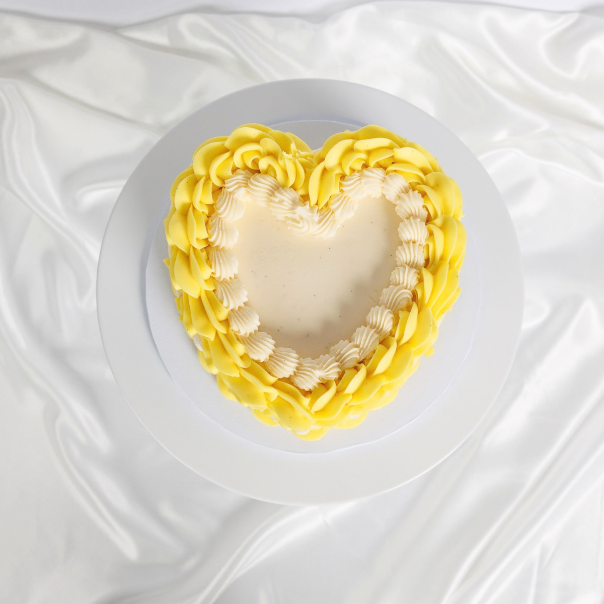 White Vintage Heart Cake with yellow buttercream trim, top view